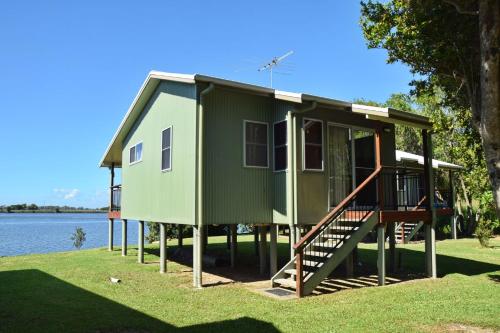 a green tiny house on the side of a lake at Coast and Country Cabin 2 in Pelican Island
