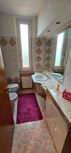a bathroom with two toilets and a purple rug at appartamento palombina vista mare in Ancona