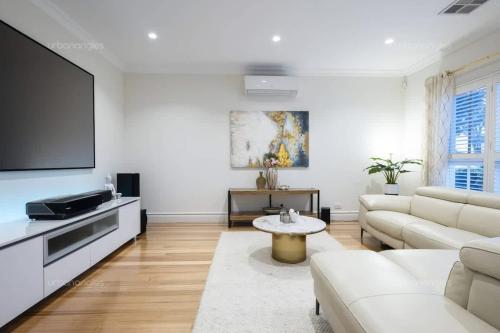 a living room with white furniture and a flat screen tv at Luxurious Georgian Style Family Home with Cinema in Templestowe Lower