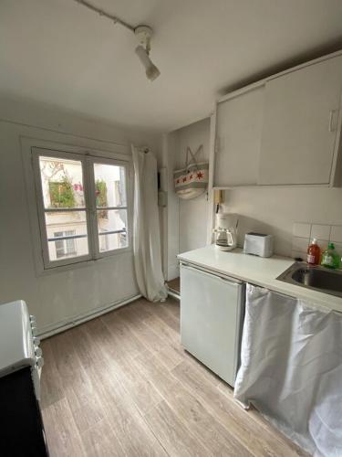 une petite cuisine avec un évier et une fenêtre dans l'établissement Romantic Studio apt Historical Center Paris Marais, à Paris