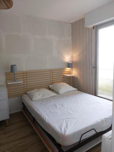 un lit dans une chambre avec une grande fenêtre dans l'établissement T2 Esplanade de la Mer, à Saint-Hilaire-de-Riez