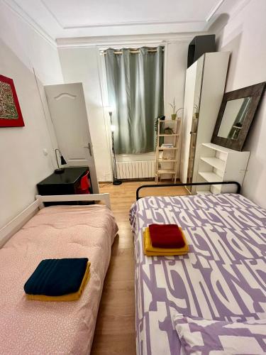 une chambre avec deux lits et un miroir dans l'établissement Coup de Cœur à Montmartre - Eugène Suë, à Paris