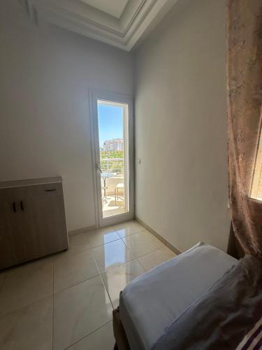 a white room with a bed and a window at Luxueux appt jardin de Carthage in La Goulette