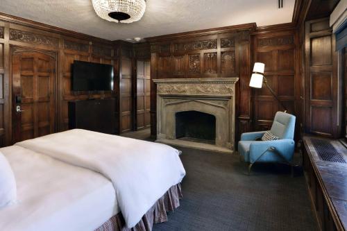 a bedroom with a fireplace and a bed and a chair at Le Meridien Dallas, The Stoneleigh in Dallas