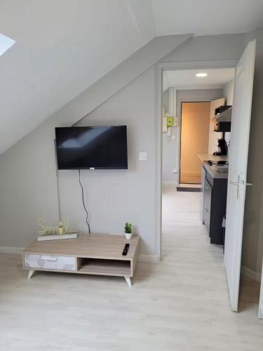 a living room with a table and a tv on the wall at Parfait F1, Entrée du Havre #11 in Le Havre