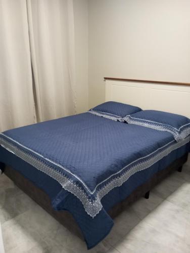 een bed met een blauw dekbed en blauwe kussens bij Apartamento Magnólia in Balneário Camboriú