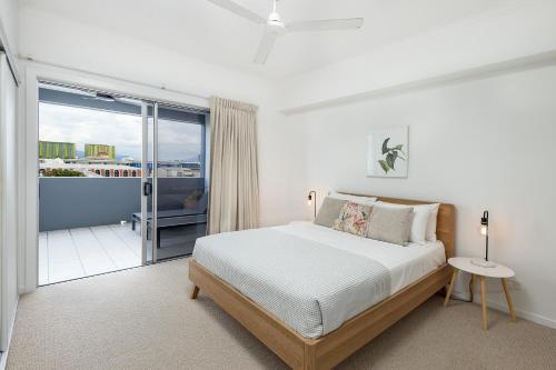 a white bedroom with a bed and a balcony at Panoramic views 3BR Cairns City Apartment in Cairns