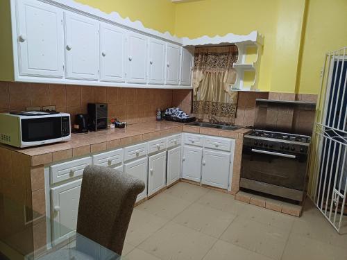 a kitchen with white cabinets and a microwave at Millennium View Villa - Castries in Castries