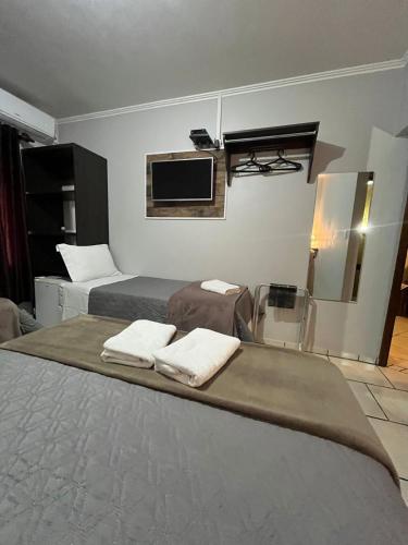 a hotel room with two beds and a flat screen tv at Familien Haus Pousada in Pomerode
