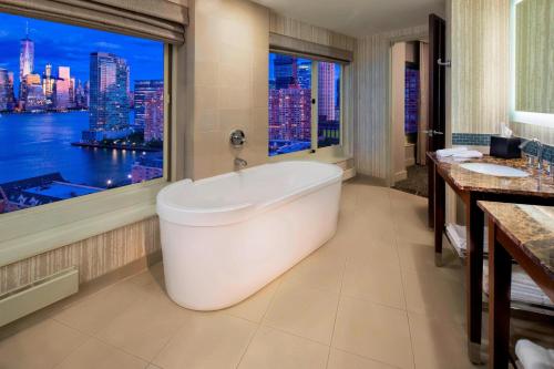 a bathroom with a tub and a large window at The Westin Jersey City Newport in Jersey City