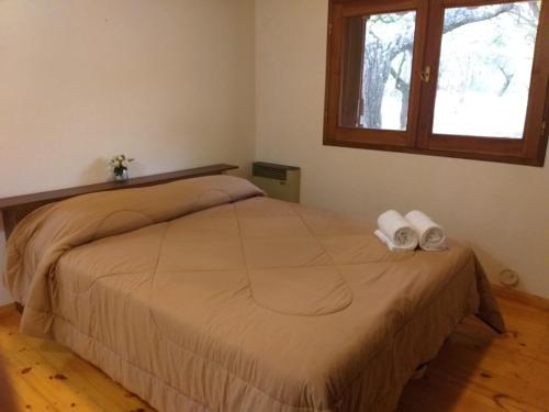 Un dormitorio con una cama con dos toallas encima. en La Almenara Lodge, en Villa General Belgrano