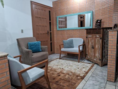 a living room with two chairs and a mirror at Casa de Veraneio in Capão da Canoa
