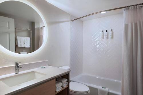 a bathroom with a sink and a toilet and a mirror at TownePlace Suites by Marriott College Station in College Station