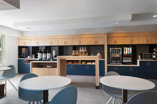 a kitchen with two tables and blue chairs at TownePlace Suites by Marriott College Station in College Station