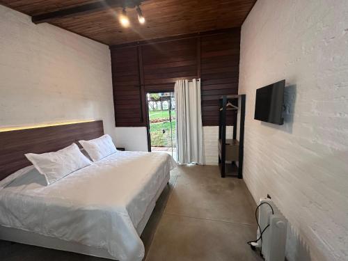 a bedroom with a bed and a tv on a wall at Cabanas All Black in Monte Verde