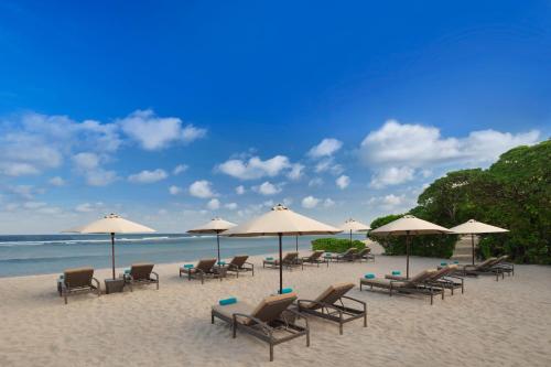 a group of chairs and umbrellas on a beach at Courtyard by Marriott Bali Nusa Dua Resort in Nusa Dua