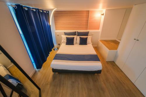 a small bedroom with a bed with blue curtains at Villa Bono Jacuzzi & Spa in Saint-Laurent-du-Var