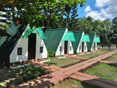 a row of white buildings with green roofs at Villa Karensa Farm in General Emilio Aguinaldo