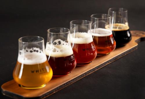 four glasses of beer on a wooden tray at Whitton Malt House in Whitton