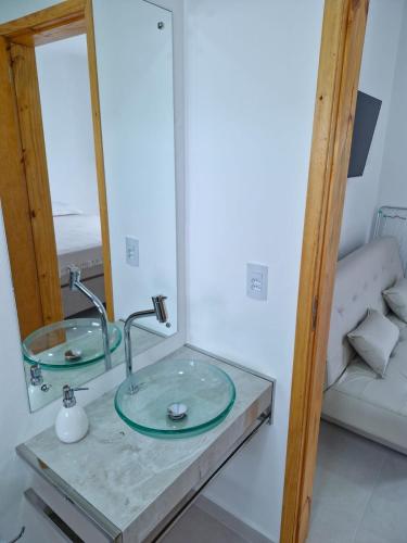 a bathroom with a glass sink and a mirror at Palo Santo - Praia do Rosa in Praia do Rosa