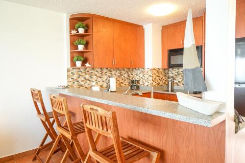 a kitchen with wooden cabinets and a counter with chairs at High Rise Beachfront condo With Panoramic Views in Fajardo