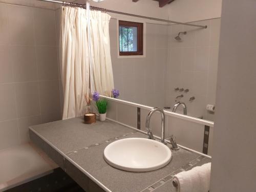 Un baño con lavabo blanco y ducha. en La Almenara Lodge, en Villa General Belgrano