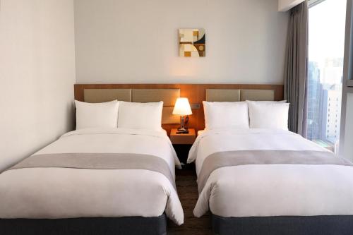 two beds in a hotel room with a window at Stanford Hotel Myeongdong in Seoul