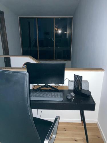 a desk with a keyboard and a laptop computer on it at Moderne og centralt rækkehus i Herning in Herning