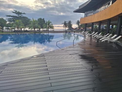 a swimming pool with white chairs next to a building at Seafront Residences Vacation Home in Batangas City