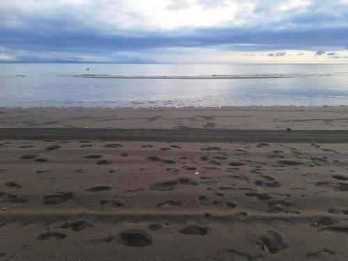 a beach with footprints in the sand and the water at Seafront Residences Vacation Home in Batangas City