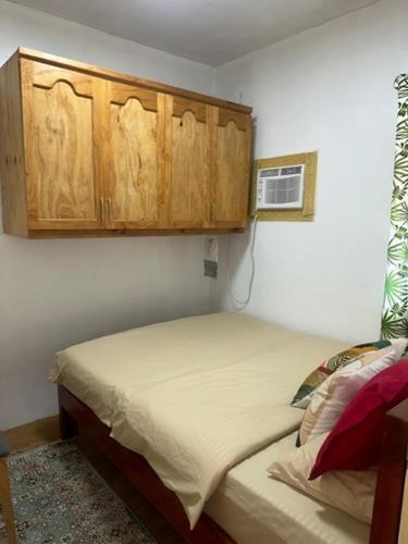 a bedroom with a bed and wooden cabinets at Laly's B8 cozy Vacation Townhouse in Olongapo