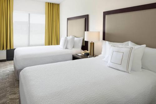ラウンドロックにあるSpringHill Suites Austin Round Rockの白い枕が置かれたホテルの部屋にはベッドが2つある