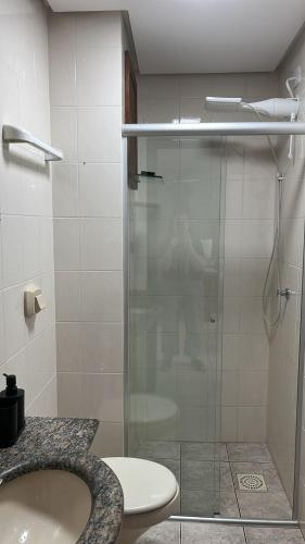 a bathroom with a shower and a sink and a toilet at Espaçoso 1 d perto do mar com vaga in Capão da Canoa