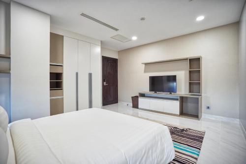 a bedroom with a white bed and a flat screen tv at URBAN PALACE in Phnom Penh