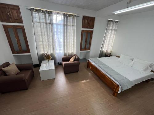 a bedroom with a bed and a couch and a chair at PuVi Homestay, Dzukou entry point in Viswema