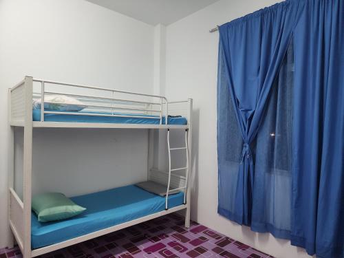 a bunk bed in a room with a blue curtain at Homestay Zaishazali in Gelugor