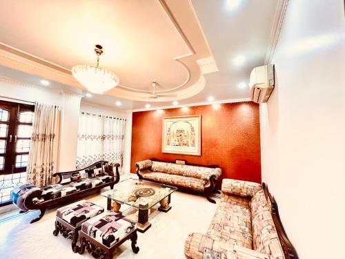 a living room with leather furniture and a chandelier at South Inn - Green Park South Delhi in New Delhi