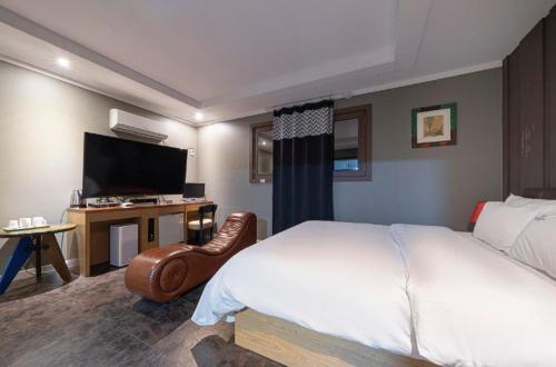 a bedroom with a bed and a desk with a television at Shampoo Hotel Incheon in Incheon