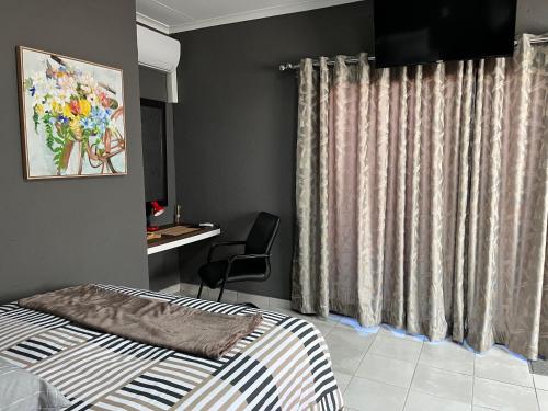 a bedroom with a bed and a chair and curtains at Família BnB in Tekwane