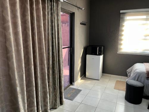 a room with a window with curtains and a television at Família BnB in Tekwane