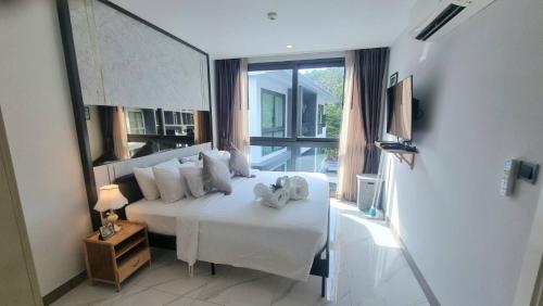 una camera da letto con un letto bianco con asciugamani sopra di B506-top Floor Pool View 1 Br At Ao Nang Beach ad Aonang Beach