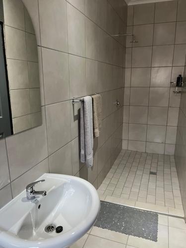 a white bathroom with a sink and a shower at Família BnB in Tekwane