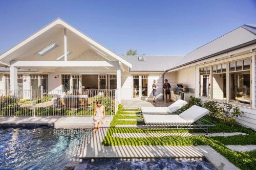 a little girl is standing in front of a house at Muskoka Luxe Retreat with Pool Spa & Fire Pit in Mount Martha