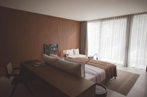 a bedroom with a bed and a desk and a window at SOKO' Stay at Kedungu in Tanah Lot