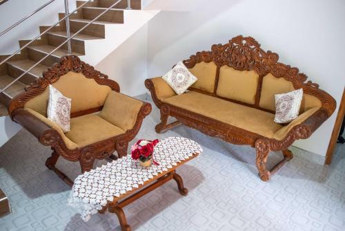 two chairs and a table in a room with stairs at AMA HomeStay in Udawalawe