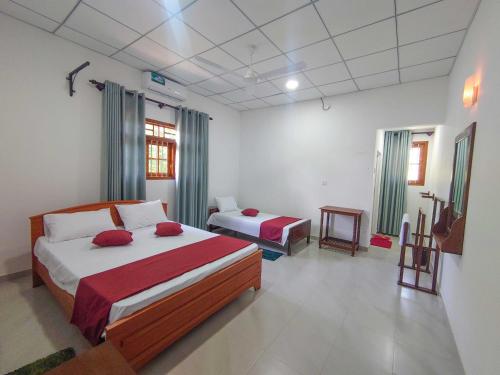 a bedroom with two beds and a tv in it at AMA HomeStay in Udawalawe