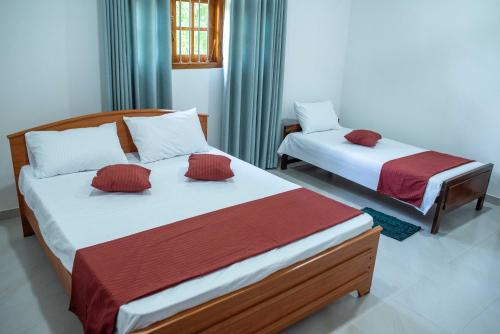 two beds are in a room withthritisthritisthritisthritisthritisthritisthritisthritisthritis at AMA HomeStay in Udawalawe