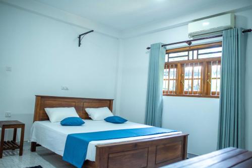 a bedroom with a bed with blue sheets and a window at AMA HomeStay in Udawalawe