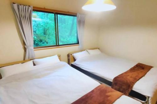 two beds in a room with a window at ユナイテッドリゾート軽井沢1 in Tsumagoi