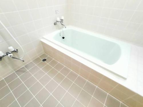 a bathroom with a tub and a tiled floor at ユナイテッドリゾート軽井沢1 in Tsumagoi